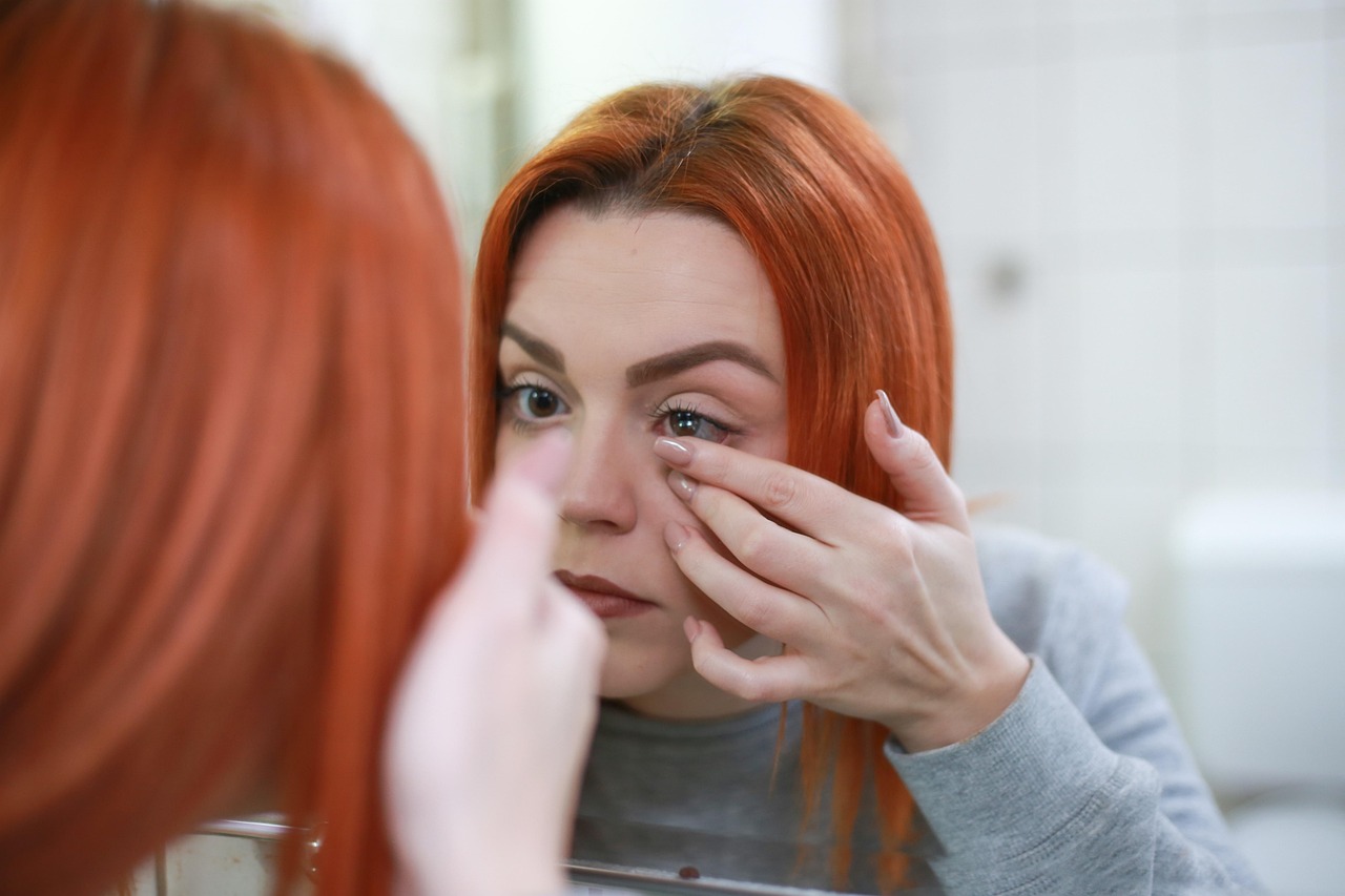 a red-head inserting a contact lense at David Fensham Optometrists